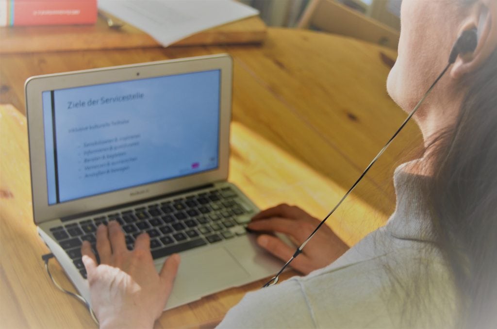 Frau bedient Laptop mit angeschlossenem Kopfhörer.