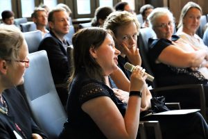 Blick ins Publikum. Eine Teilnehmerin hält eine Mikrophon in der Hand