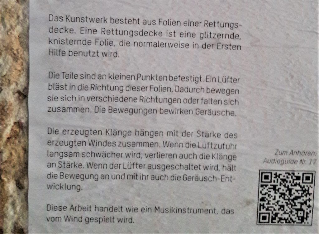 Das Foto zeigt einen Text auf weißem Papier, der an einer Wand klebt.