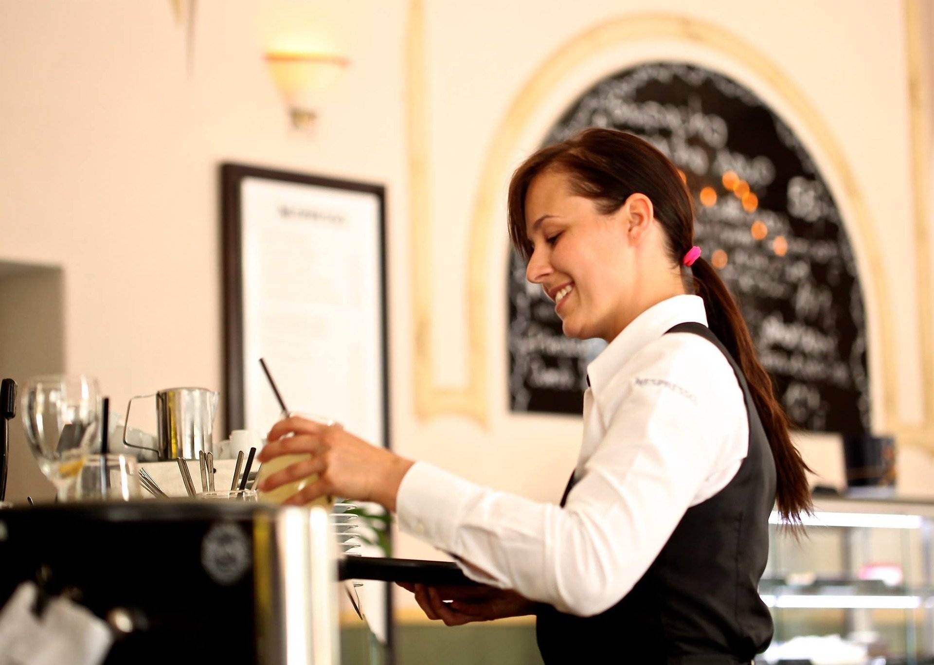 Das Foto zeigt eine Servicemitarbeiterin in einem Cafe an einer Kaffeemaschine.