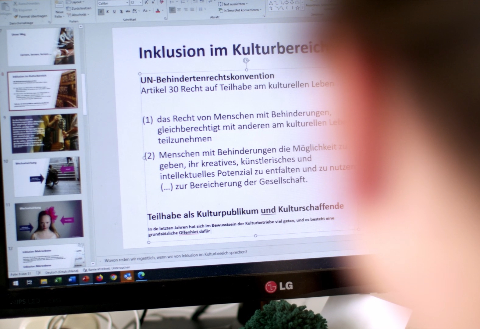 Bildschirm mit Text zur UN-BRK, davor ein unscharfer Ausschnitt eines Kopfes.